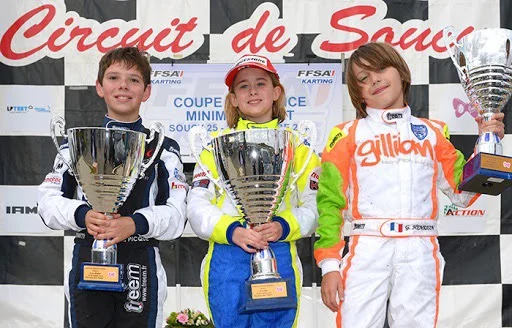Gillian enfant sur un podium de karting, coupe en main